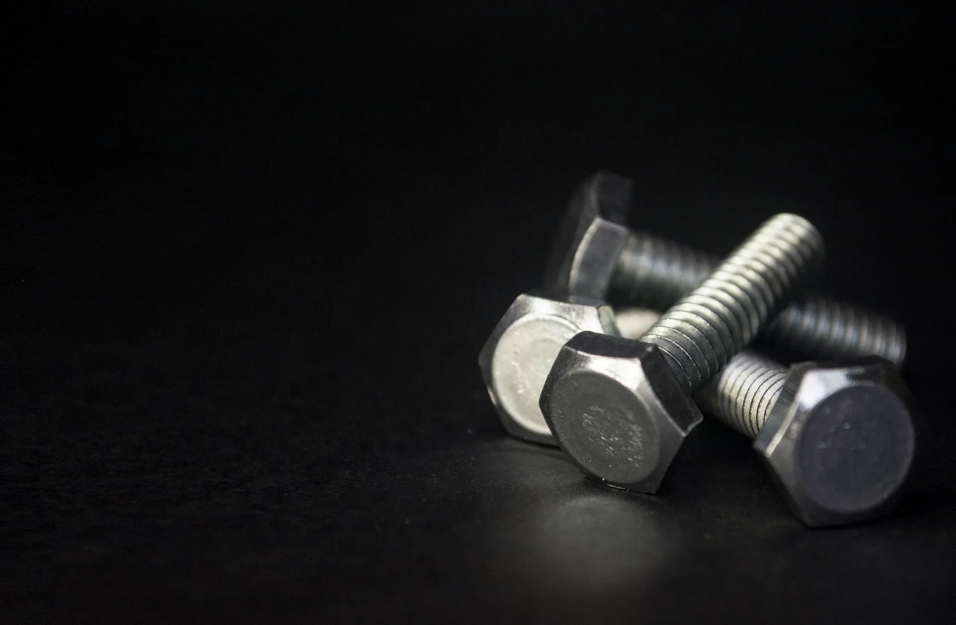 Industry context: Two threaded hex-head bolts on a dark background.